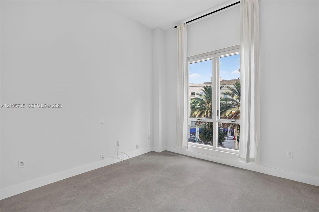 High-ceilinged room featuring expansive floor-to-ceiling windows, neutral tile flooring, and clean-lined architectural walls