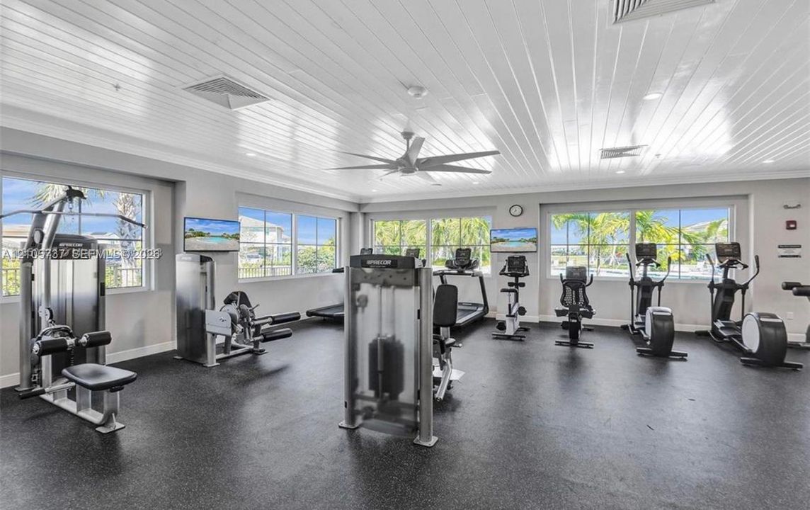 Fitness center featuring high-gloss tongue-and-groove ceilings, recessed lighting, expansive multi-pane windows, and durable rubberized flooring