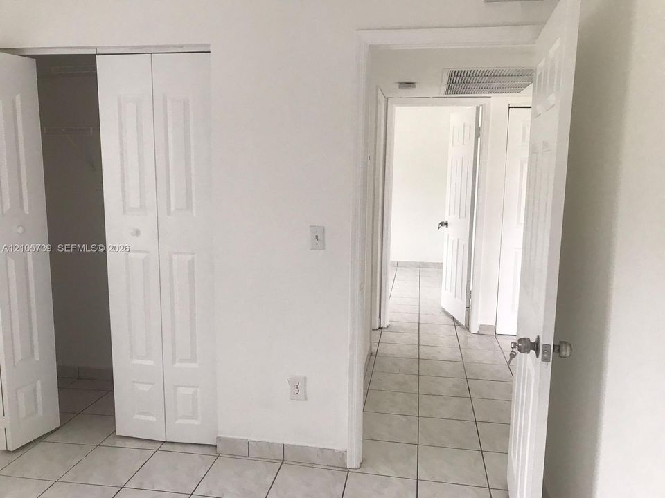 Interior space featuring light-colored tile flooring, white panel doors, and built-in closet storage