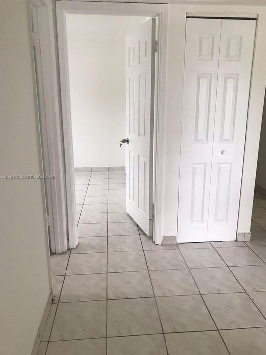 Ceramic tile flooring, six-panel interior swing door, and bifold closet door