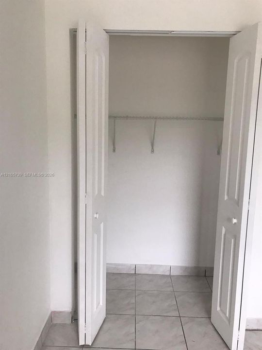 Closet featuring white paneled bifold doors, tile flooring, and built-in wire shelving