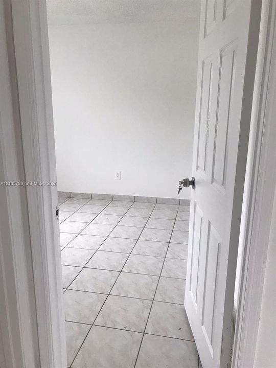 Interior space featuring neutral wall tones, large-format tile flooring, and a classic six-panel white door