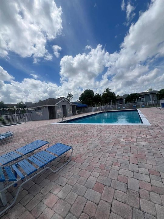 Swimming pool featuring a brick paver deck, metal pool ladder, and enclosed masonry cabana