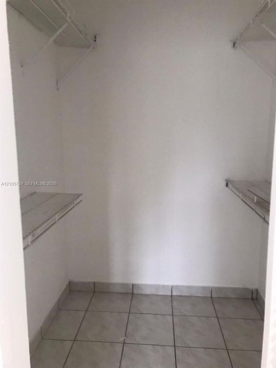 Reach-in closet featuring neutral tile flooring, white wall finishes, and integrated wire shelving