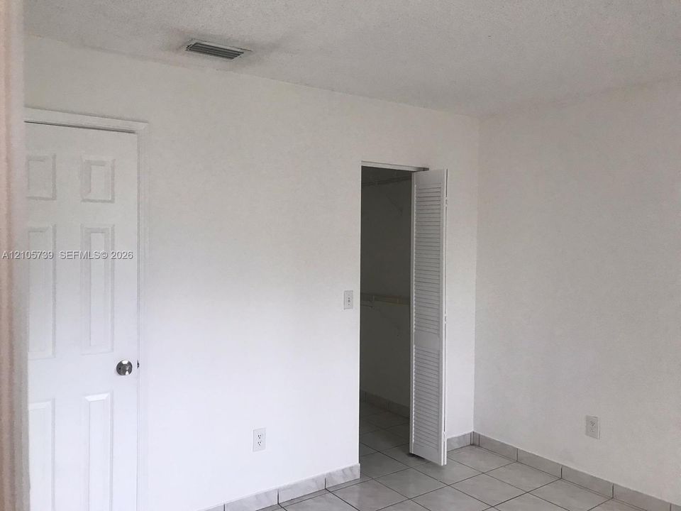 Interior space featuring ceramic tile flooring, a six-panel door, and a louvered closet door