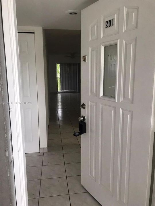Entryway featuring a white paneled door with a glass insert, light-toned tiled flooring, and a two-panel closet door