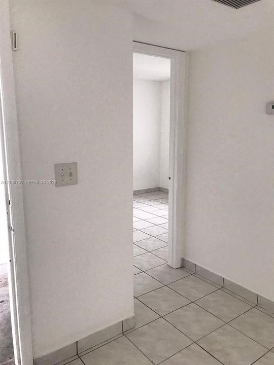 Neutral interior space featuring ceramic tile flooring, solid-surface walls, and a recessed doorway