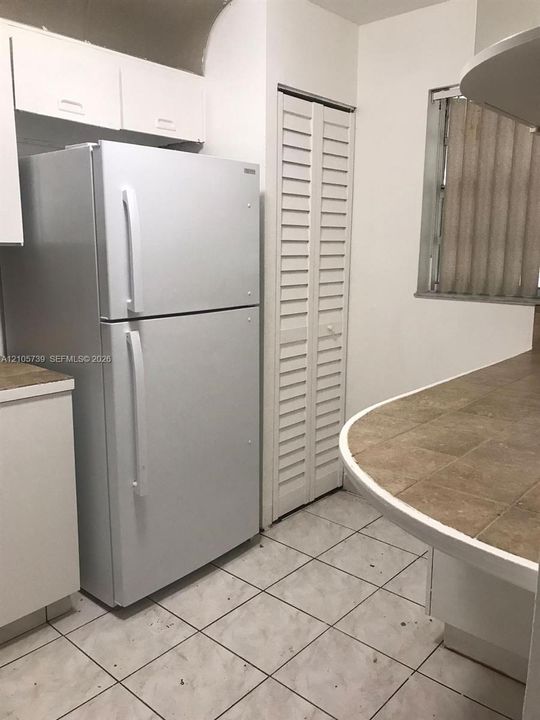Kitchen featuring white cabinetry, tiled countertop, ceramic tile flooring, and bi-fold closet doors