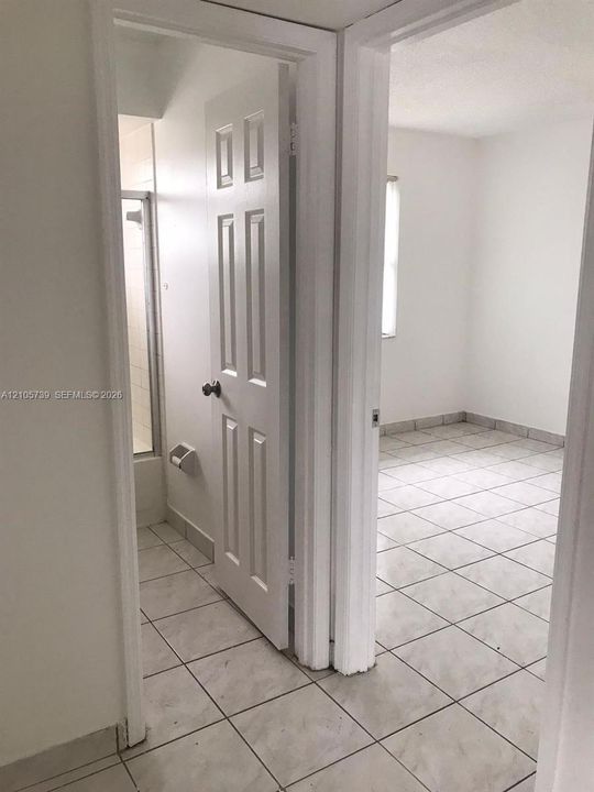 Ceramic tile flooring, white six-panel doors, and a tiled shower enclosure