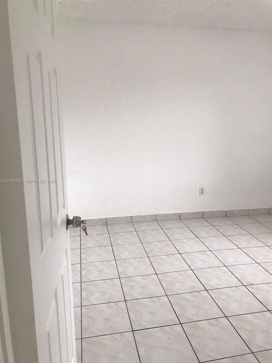 Interior space featuring white-painted walls and light-toned, square ceramic floor tiling