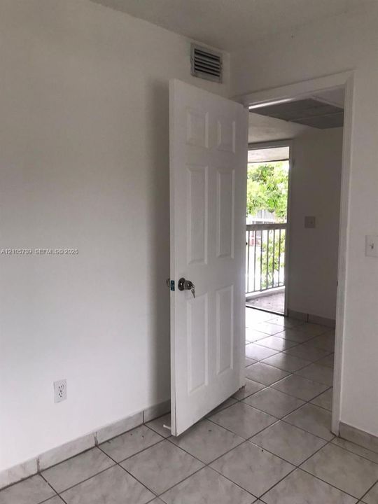 Interior space featuring light-toned ceramic tile flooring and a six-panel door with a keyed entry lock