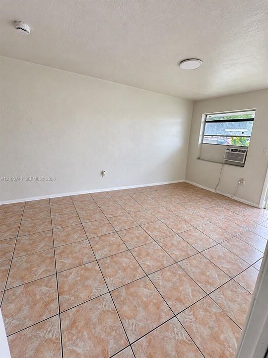 Neutral interior space featuring large-format stone-style floor tile, smooth finish walls, and a recessed ceiling lighting fixture