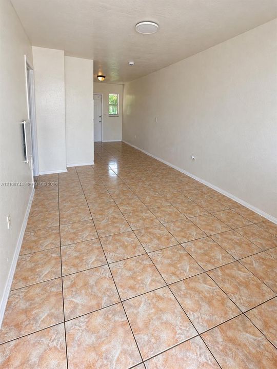 Interior space featuring neutral wall tones, large-format tile flooring, flush-mount ceiling lighting, and a white paneled door