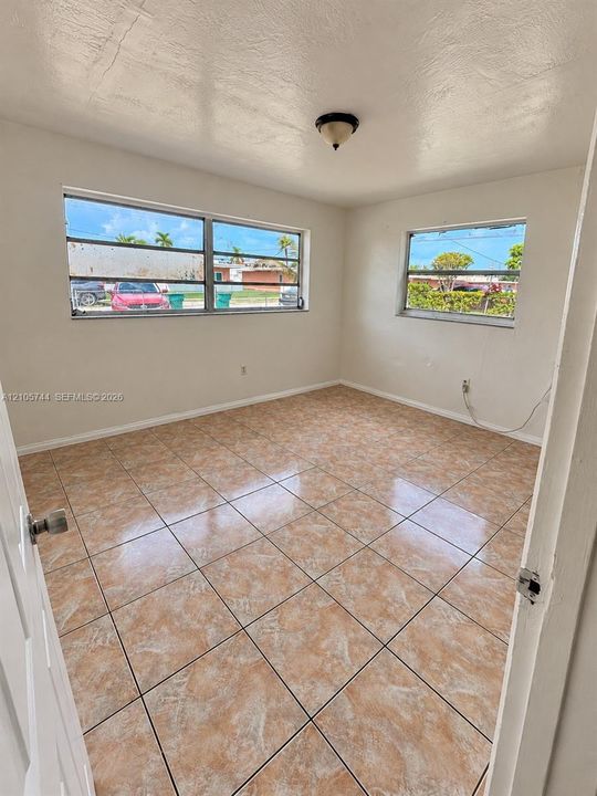 Interior space featuring polished ceramic tile flooring, neutral wall finishes, large horizontal sliding windows, and a flush-mount ceiling light fixture