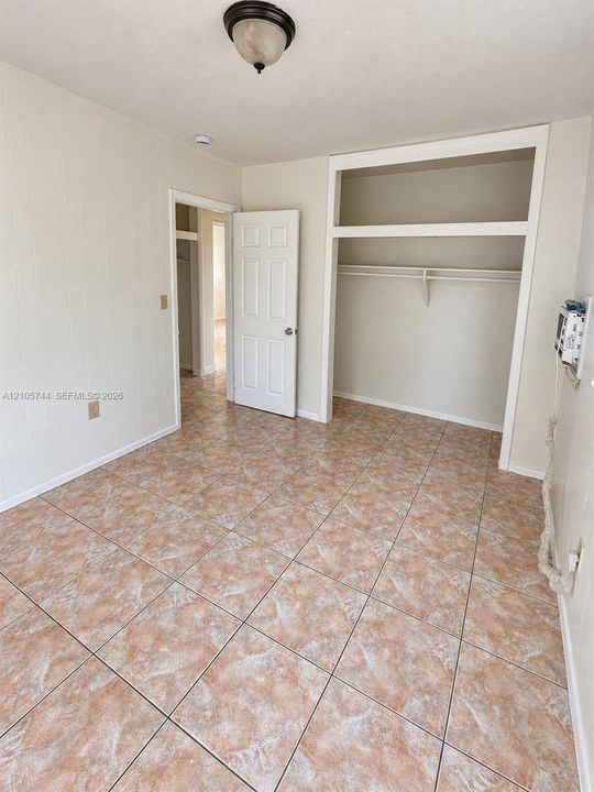 Room featuring tile flooring, neutral wall finishes, a built-in closet with overhead shelving, and a six-panel interior door