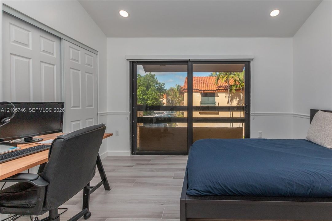 Vaulted ceiling with recessed lighting, sliding glass door, wood-finish flooring, and white wainscoting