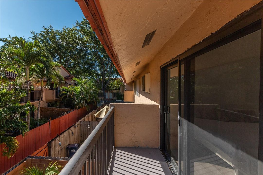 Private balcony featuring metal railings, smooth stucco exterior walls, and sliding glass door entry