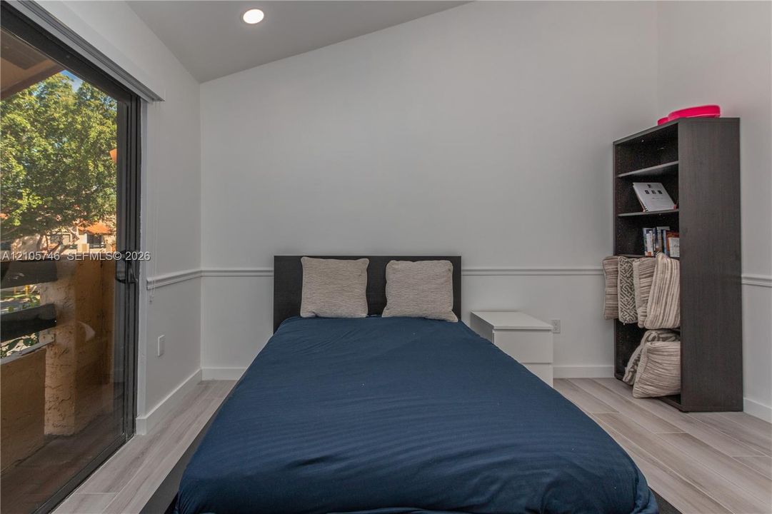 Sloped ceiling featuring recessed lighting, sliding glass door, wood-finish flooring, and chair rail molding