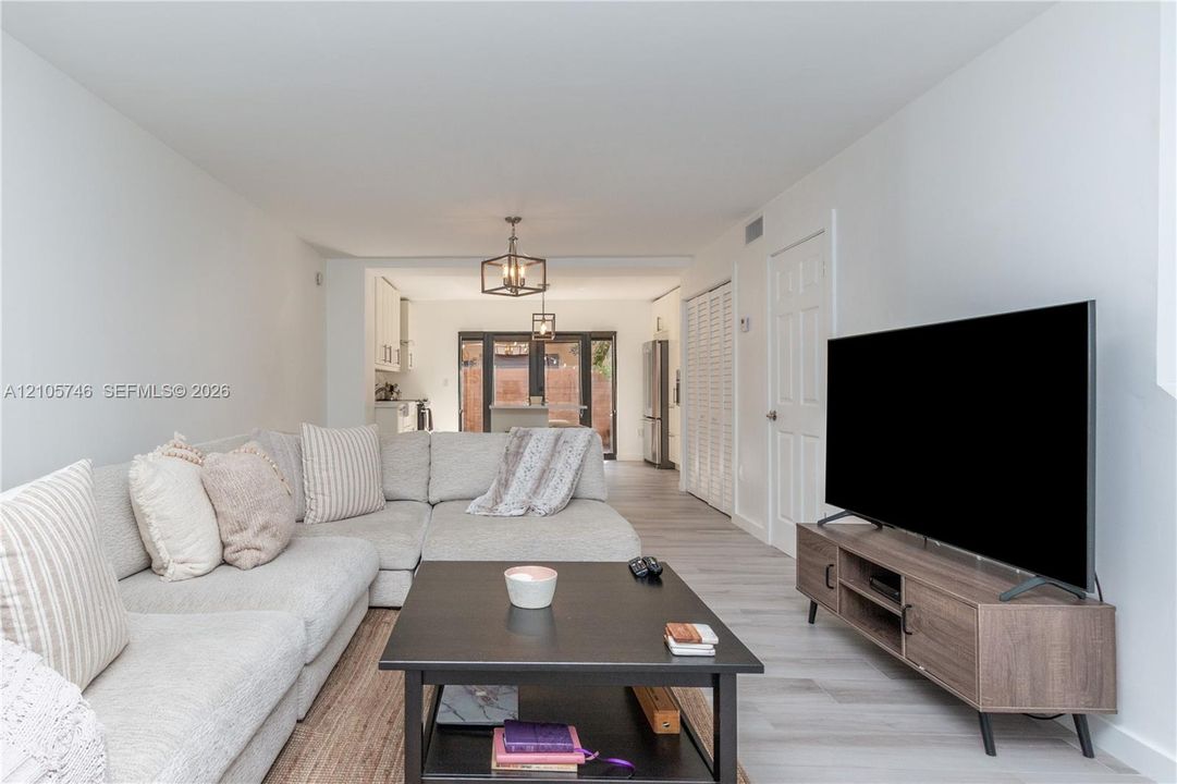 Wood-finish flooring, neutral walls, lantern-style pendant lighting, and louvered closet doors
