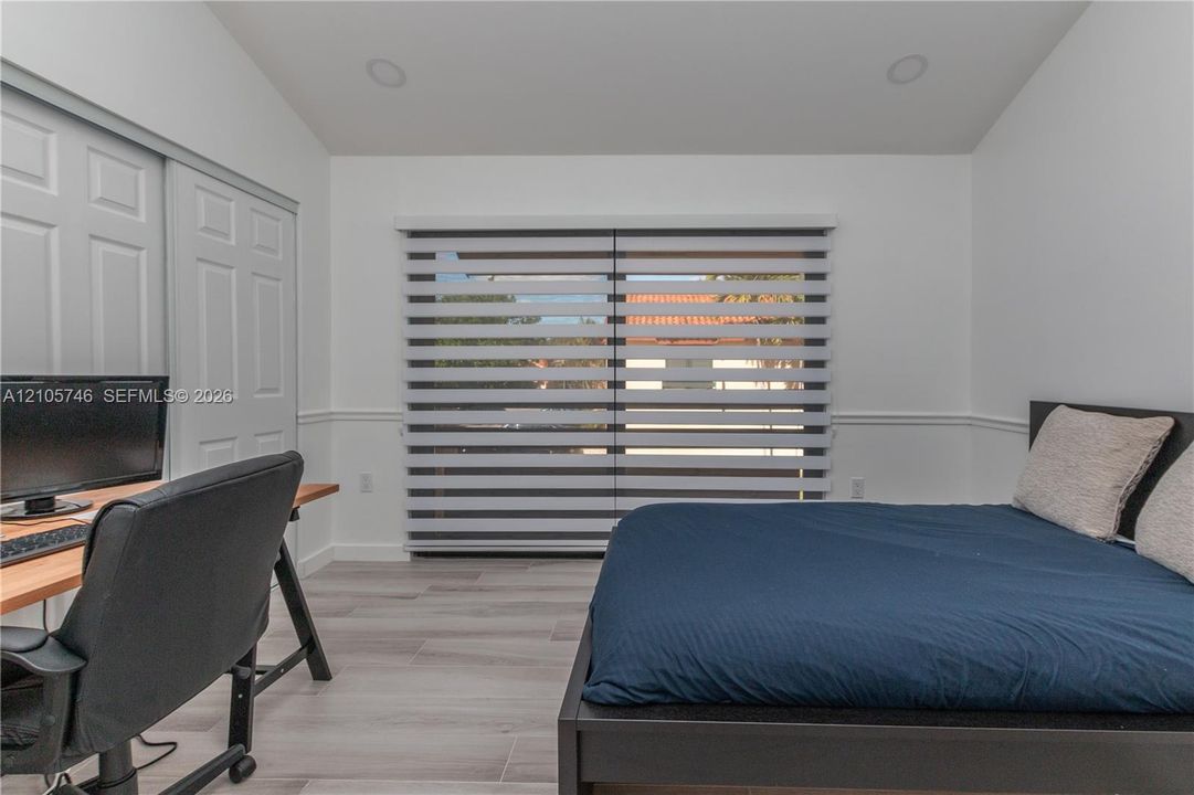 Room featuring wood-finish tile flooring, recessed lighting, chair rail molding, and a sliding-door closet
