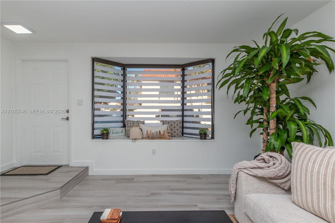 Bay window featuring tiered dual-shade blinds and a built-in window seat, wood-finish flooring, and recessed LED ceiling lighting
