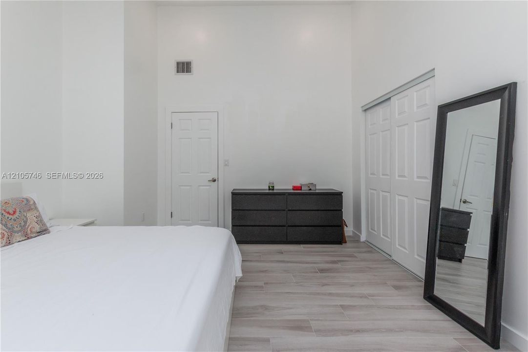 High-ceiling room with wood-finish flooring, sliding bi-fold closet doors, and a paneled entry door