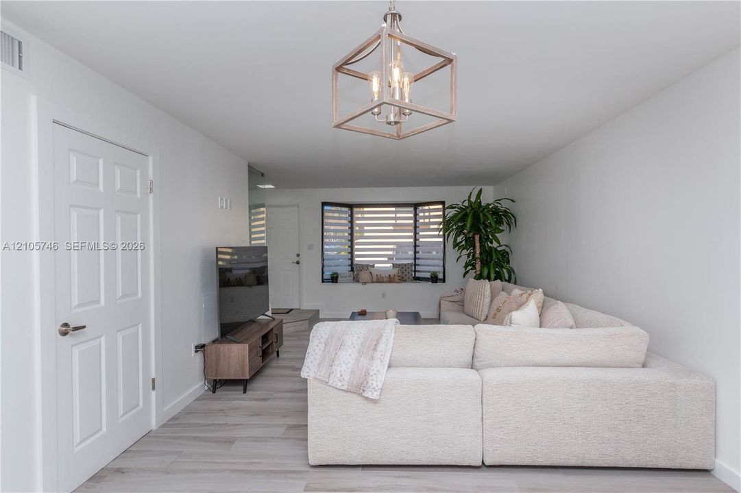 Interior space featuring wood-finish flooring, a contemporary geometric pendant light fixture, a bay window with integrated bench seating, and a multi-panel door