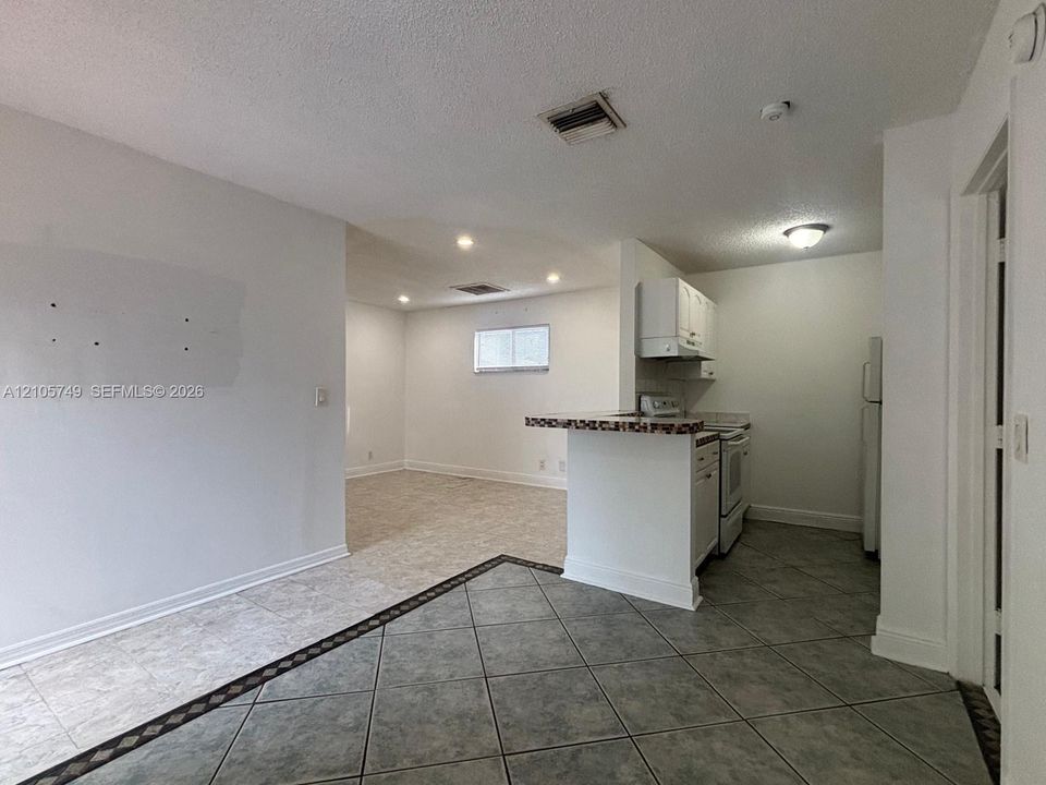 Kitchen featuring a breakfast bar, white cabinetry, and tile flooring with decorative inlay