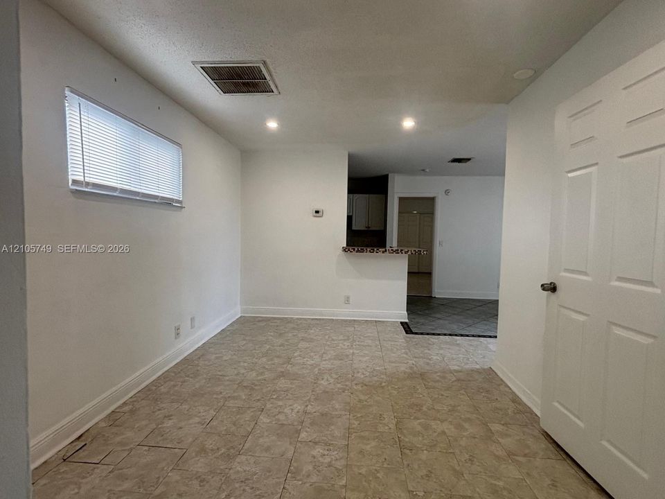 Interior space featuring neutral-toned tile flooring, recessed ceiling lighting, a horizontal window with integrated blinds, and a built-in counter surface