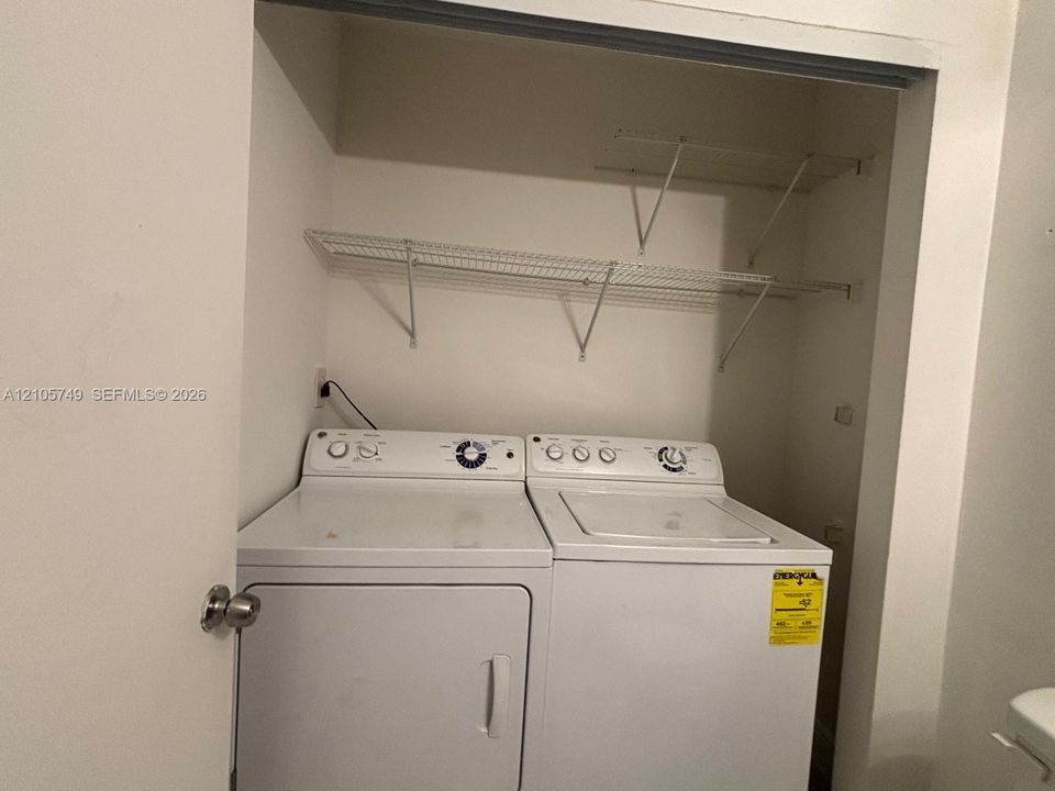 Laundry closet featuring white top-loading appliances and installed wire shelving