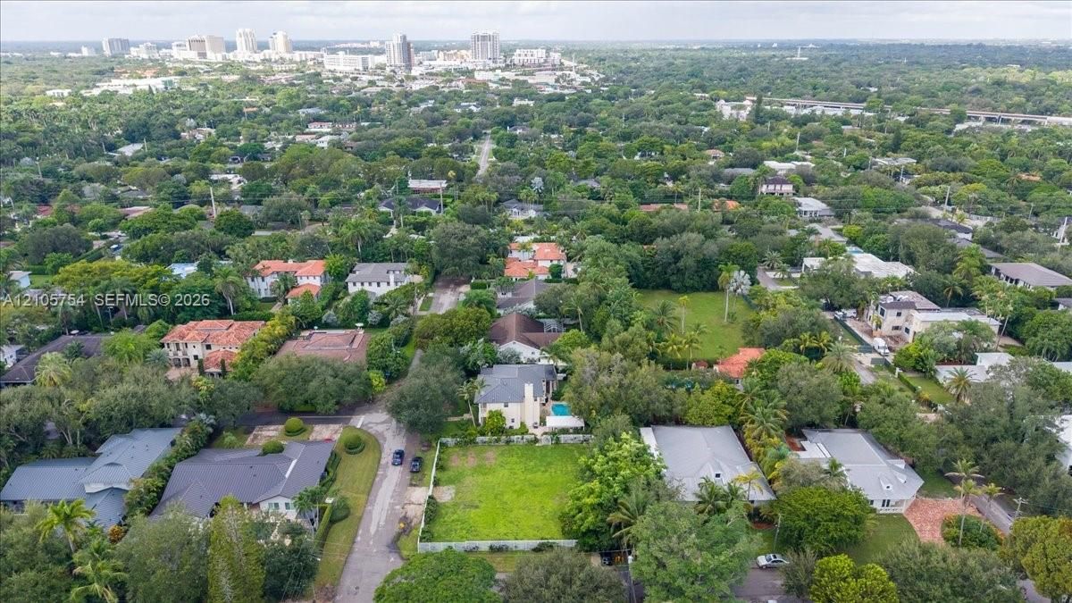 Aerial perspective of a corner lot situated in a tree-lined residential neighborhood with proximity to the urban skyline