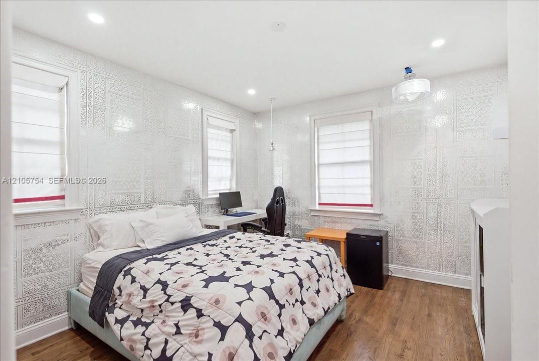 Patterned wall coverings, wood-finish flooring, recessed lighting, and three multi-pane windows with integrated window treatments