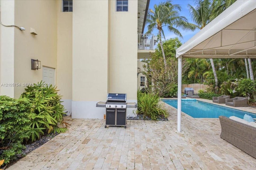 Outdoor living area featuring a stone paver patio, swimming pool, and structural metal-frame canopy