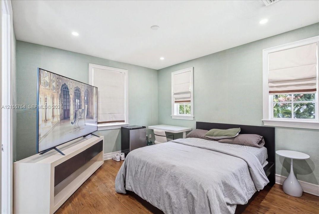 Room featuring wood-finish flooring, recessed lighting, and multiple windows with integrated window treatments