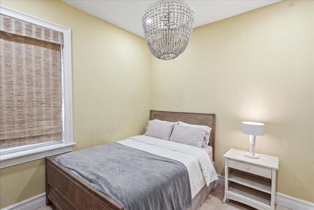 Beaded chandelier fixture, window with natural woven shade, and neutral wall paint