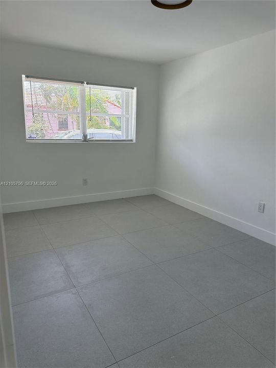 Neutral-toned interior featuring large-format ceramic floor tiles, smooth white walls, and a multi-pane horizontal window