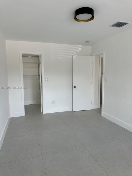 Neutral-toned ceramic tile flooring, clean white wall finishes, and a contemporary flush-mount ceiling fixture with metallic trim