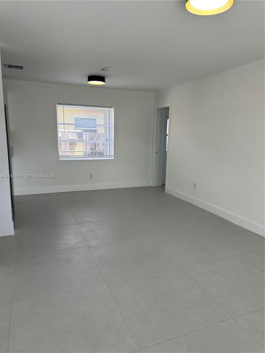 Neutral-toned room featuring large-format ceramic tile flooring, clean white walls, and contemporary flush-mount ceiling lighting