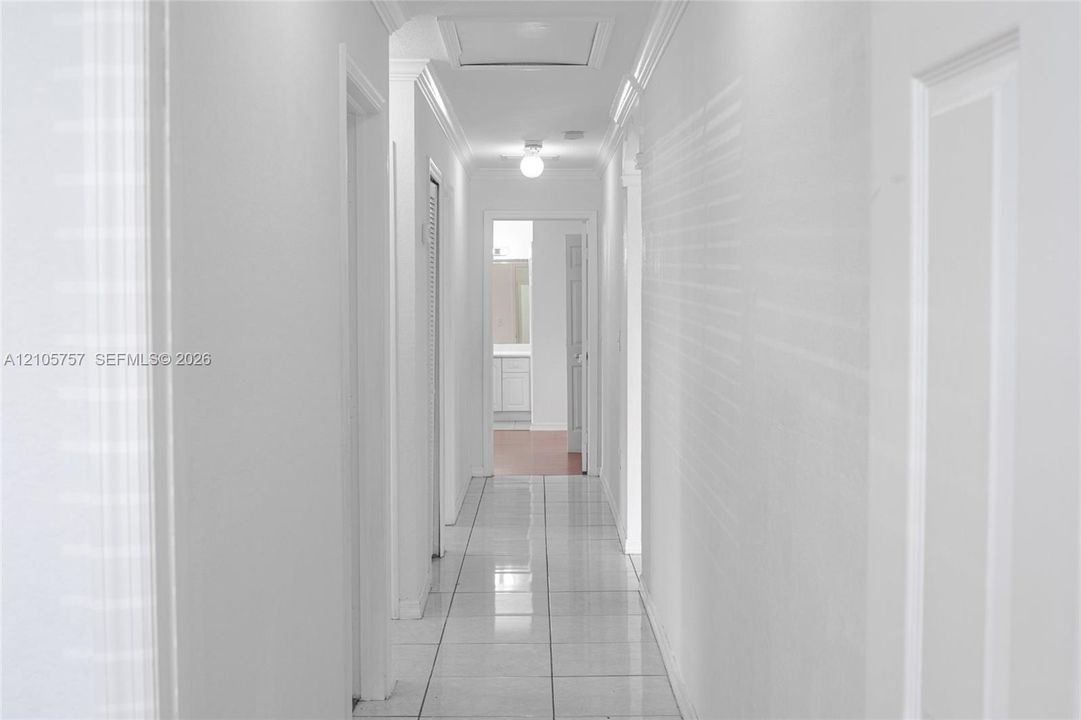Hallway featuring ceramic tile flooring, crown molding, and ceiling-mounted light fixtures