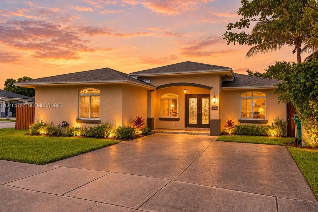 Stucco exterior featuring an arched entryway, double front doors with decorative glass inserts, and a concrete driveway