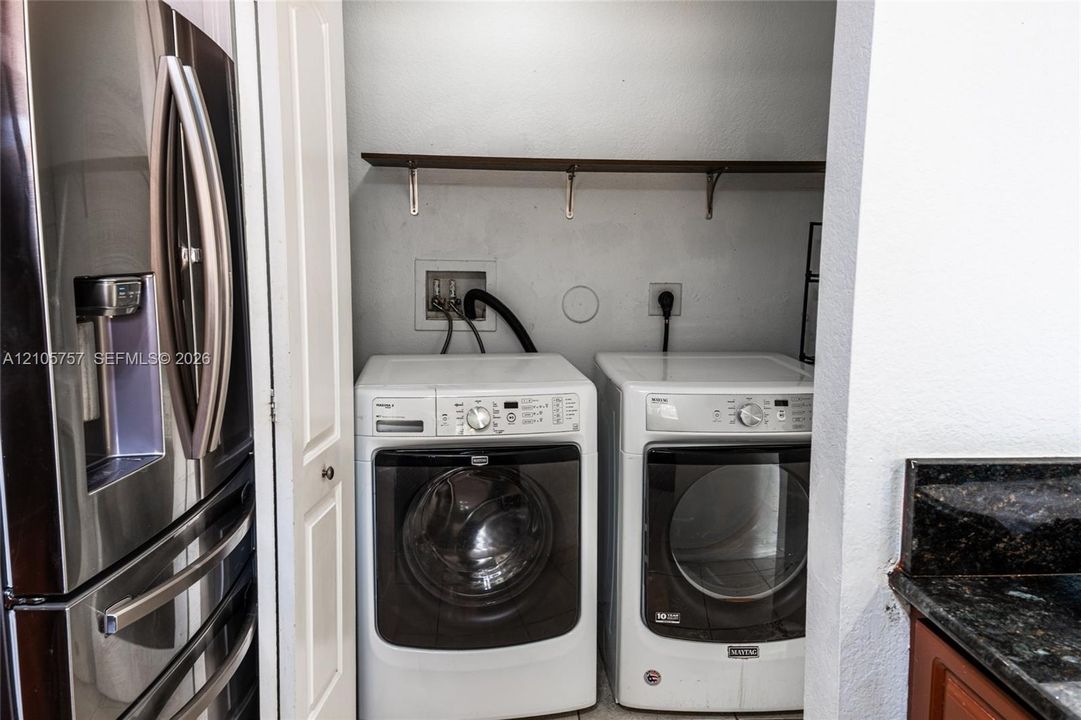 Laundry closet featuring built-in shelving, water hookups, and dedicated electrical outlets
