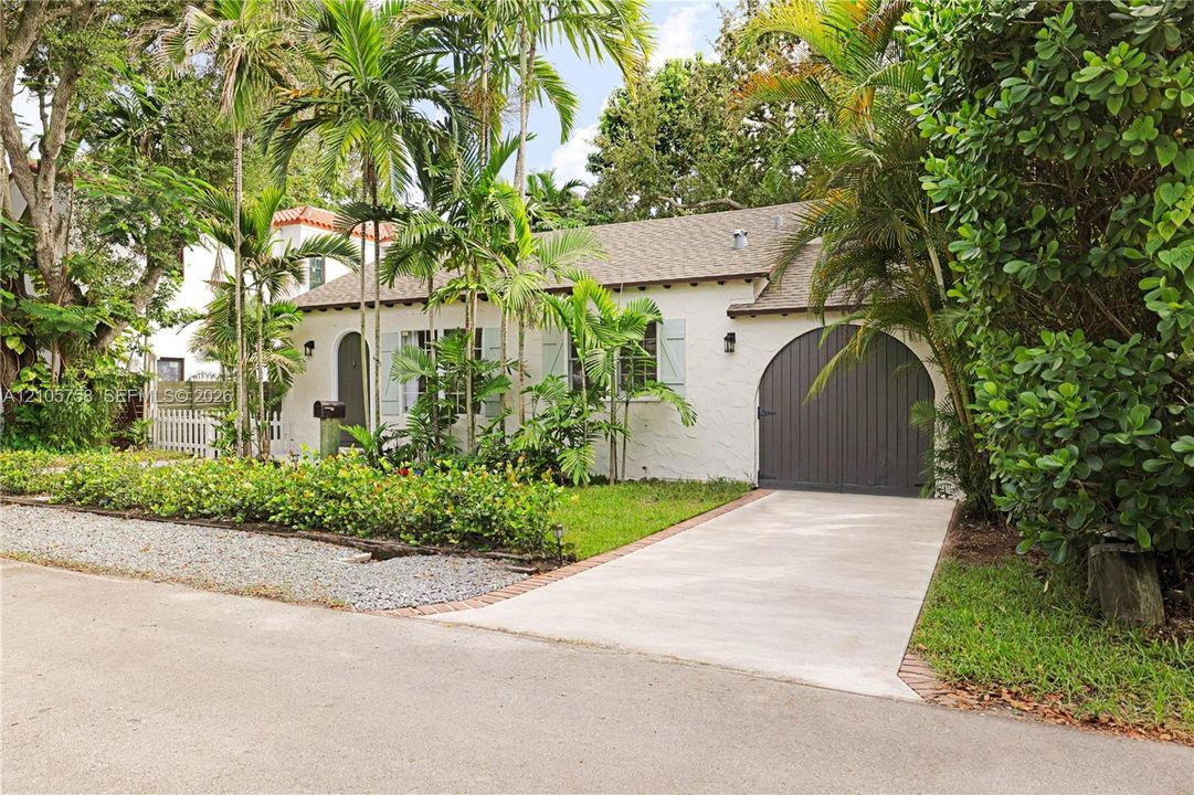 Single-story residence featuring a textured stucco exterior, arched front entryway, arched garage door, shuttered windows, and a concrete driveway