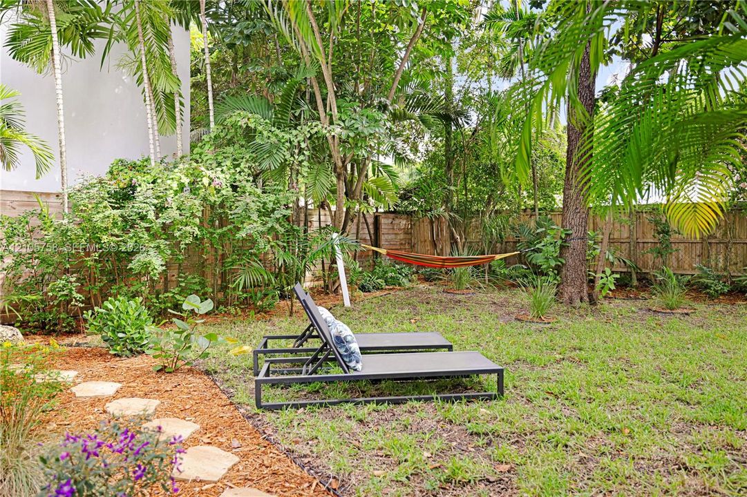 Private backyard featuring mature landscaping, natural stone pavers, and perimeter wood fencing