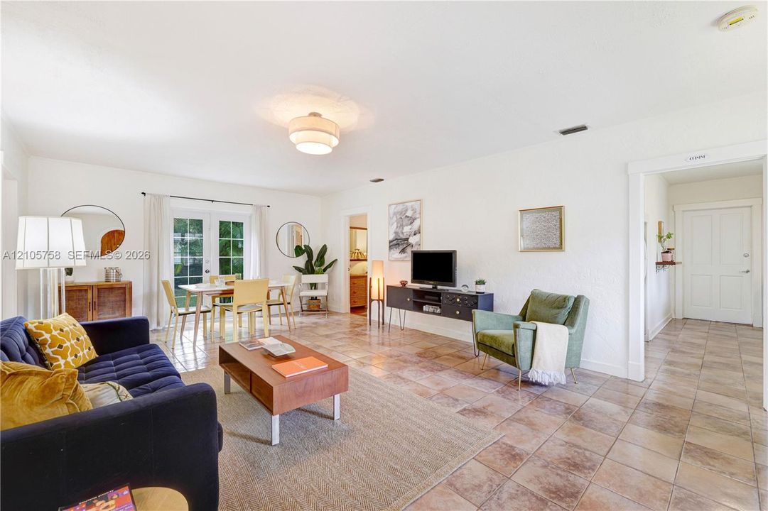 Living area featuring square tile flooring, semi-flush mount ceiling lighting, and glass-paneled double doors