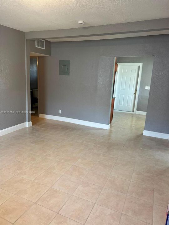Neutral-toned interior featuring ceramic tile flooring, textured wall surfaces, and a multi-panel exterior door