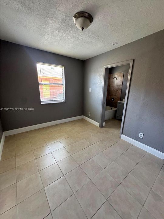 Room featuring neutral-toned tile flooring, gray-painted walls, and a dome-style flush-mount ceiling light fixture