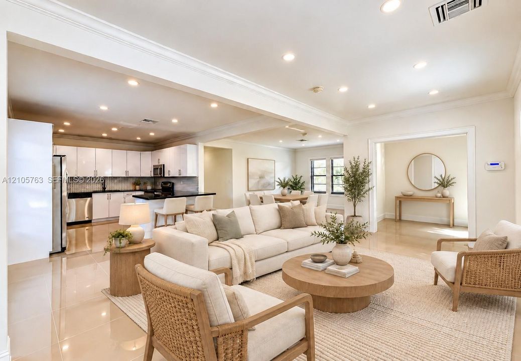 Open-concept interior featuring recessed lighting, polished tile flooring, crown molding, and a kitchen equipped with white cabinetry and dark countertops