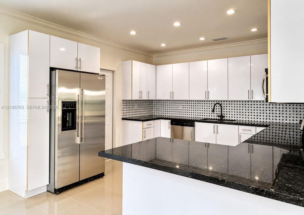 Kitchen featuring white cabinetry, dark stone-finish countertops, stainless steel appliances, a decorative tile backsplash, and recessed lighting