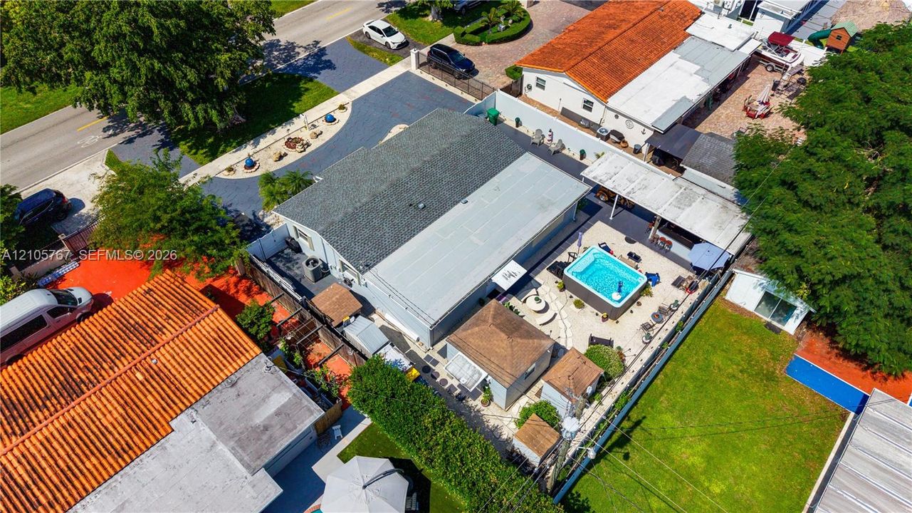 Aerial view of property featuring a private pool, covered patio area, hardscaped outdoor living space, perimeter fencing, and established lawn