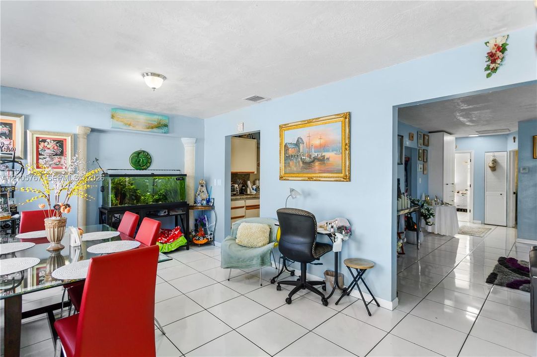 Open floor plan featuring large-format tile flooring, decorative architectural columns, and recessed lighting